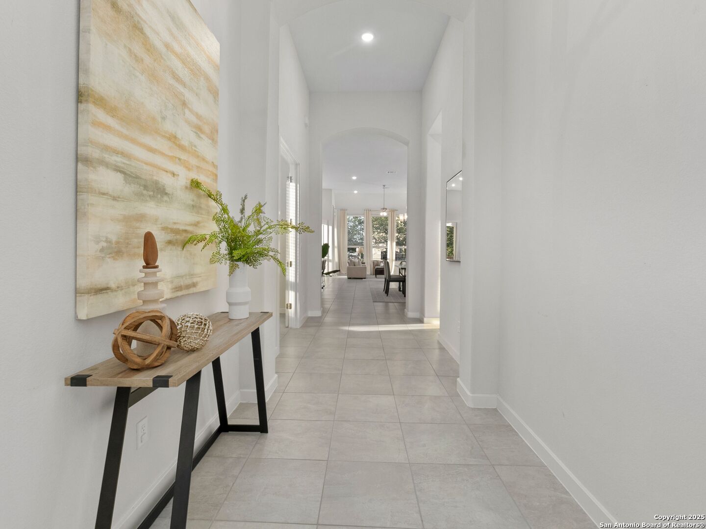 Tiled entry hallway with a console table and abstract artwork, opening toward the living and dining area.