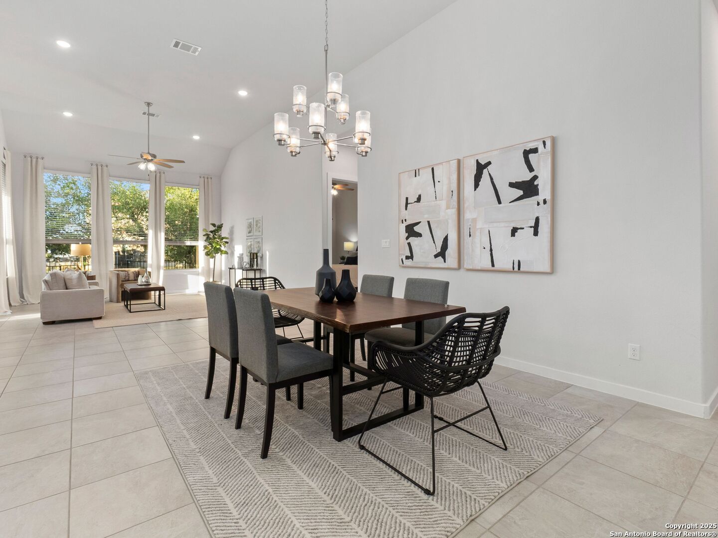 Dining room with a dark wood table, modern chandelier, and open connection to the living area.