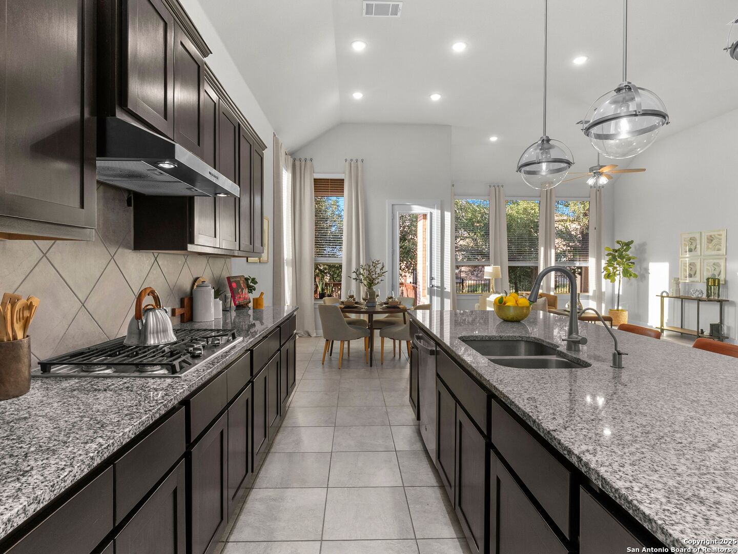 Kitchen with dark wood cabinets, granite counters, and a large island overlooking the dining area.