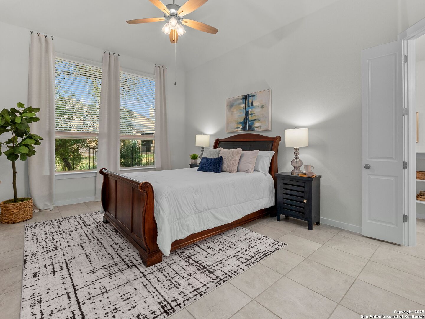Furnished bedroom with a dark wood sleigh bed, patterned rug, and two bright windows.