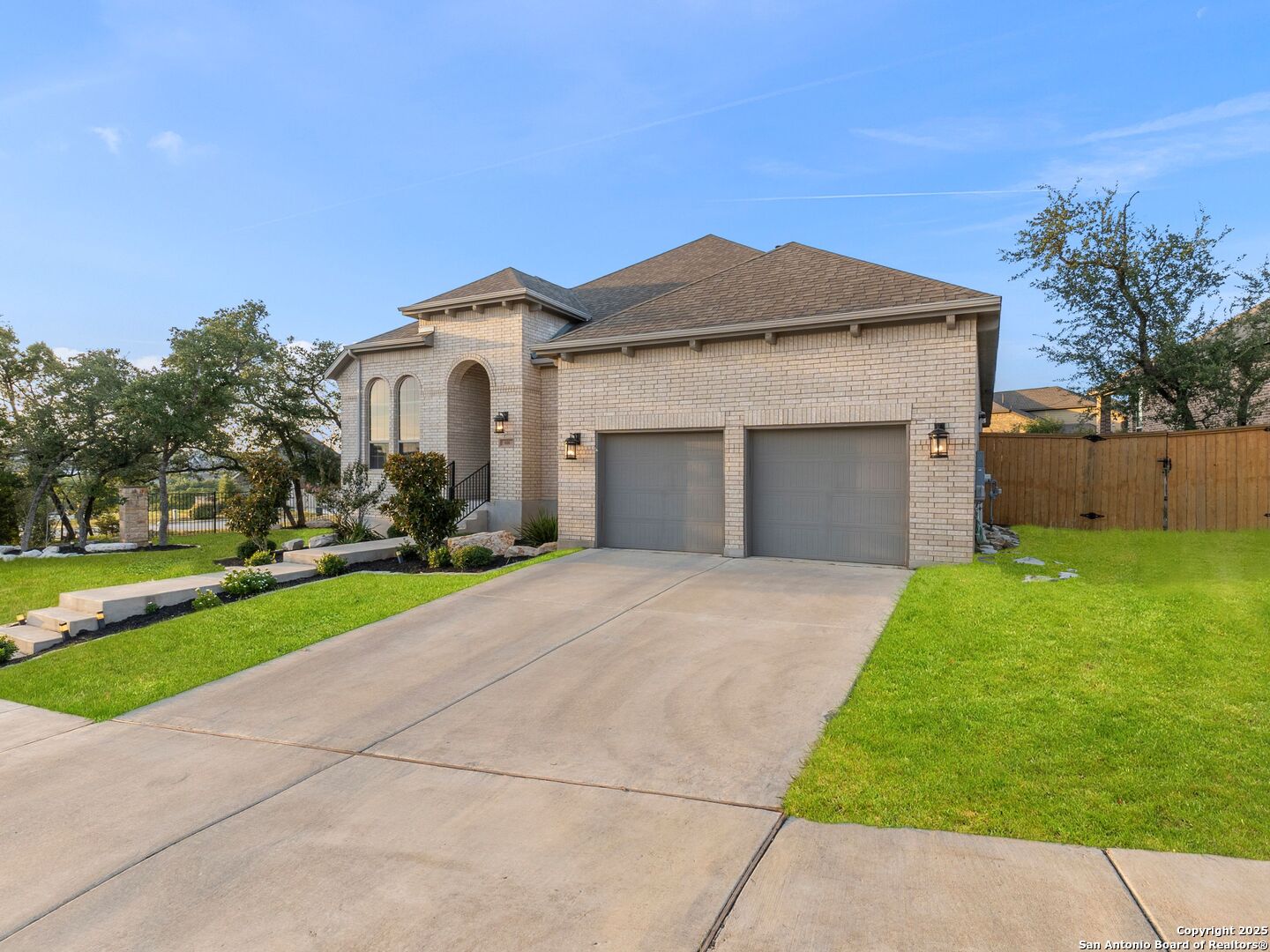 Light-brick house with a two-car garage, arched entry, and broad concrete driveway.