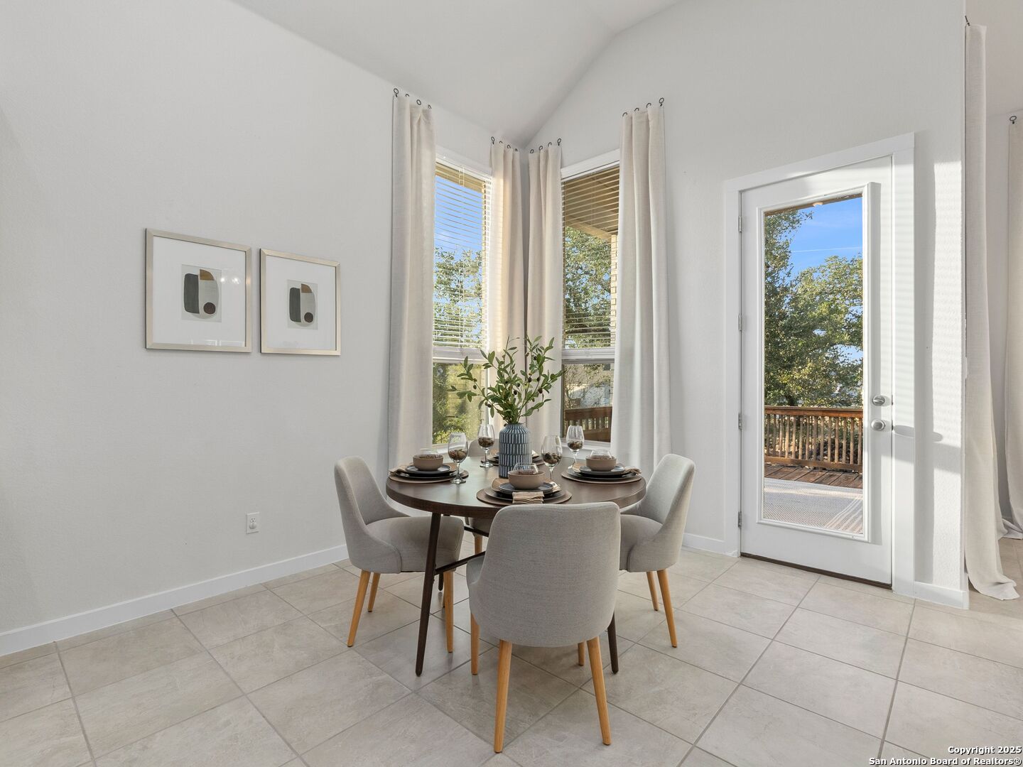 Dining area with a round set table beside corner windows and a glass door to the deck.