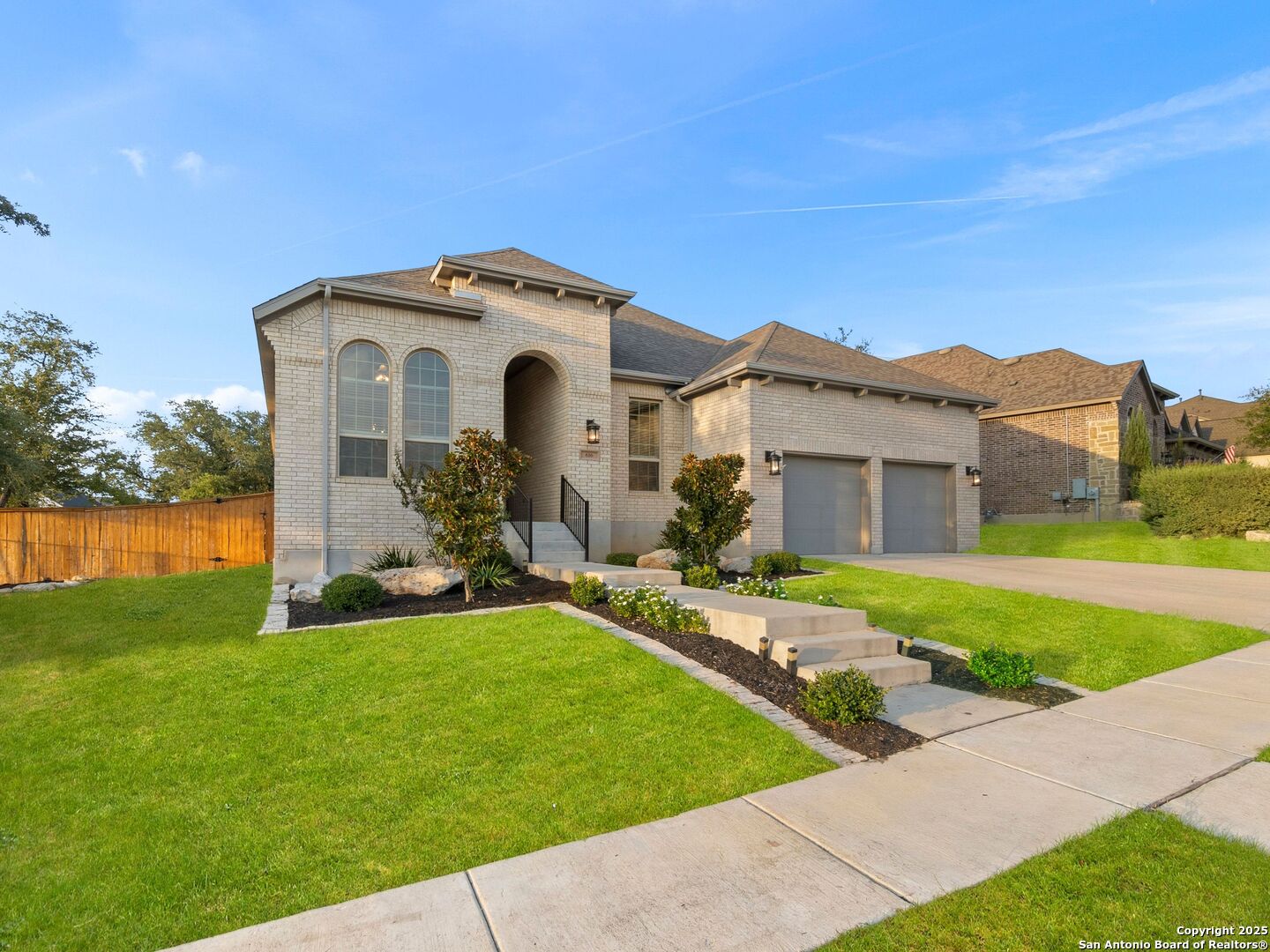 Light-brick house with an arched entry, two-car garage, and landscaped front lawn.