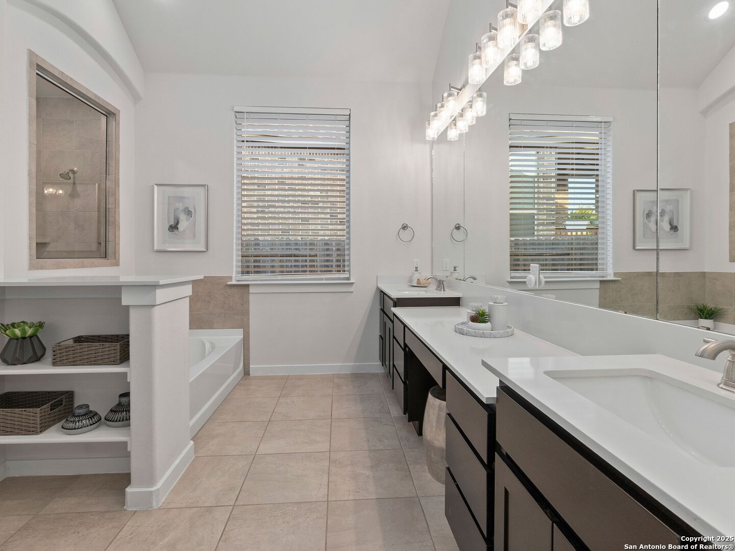 Bathroom with a long double vanity, large mirrors, tiled floors, and a built-in tub beside a glass shower.