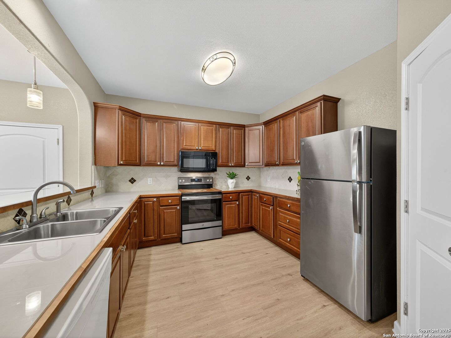 Kitchen with dark wood cabinets, stainless steel appliances, and a double-basin sink.