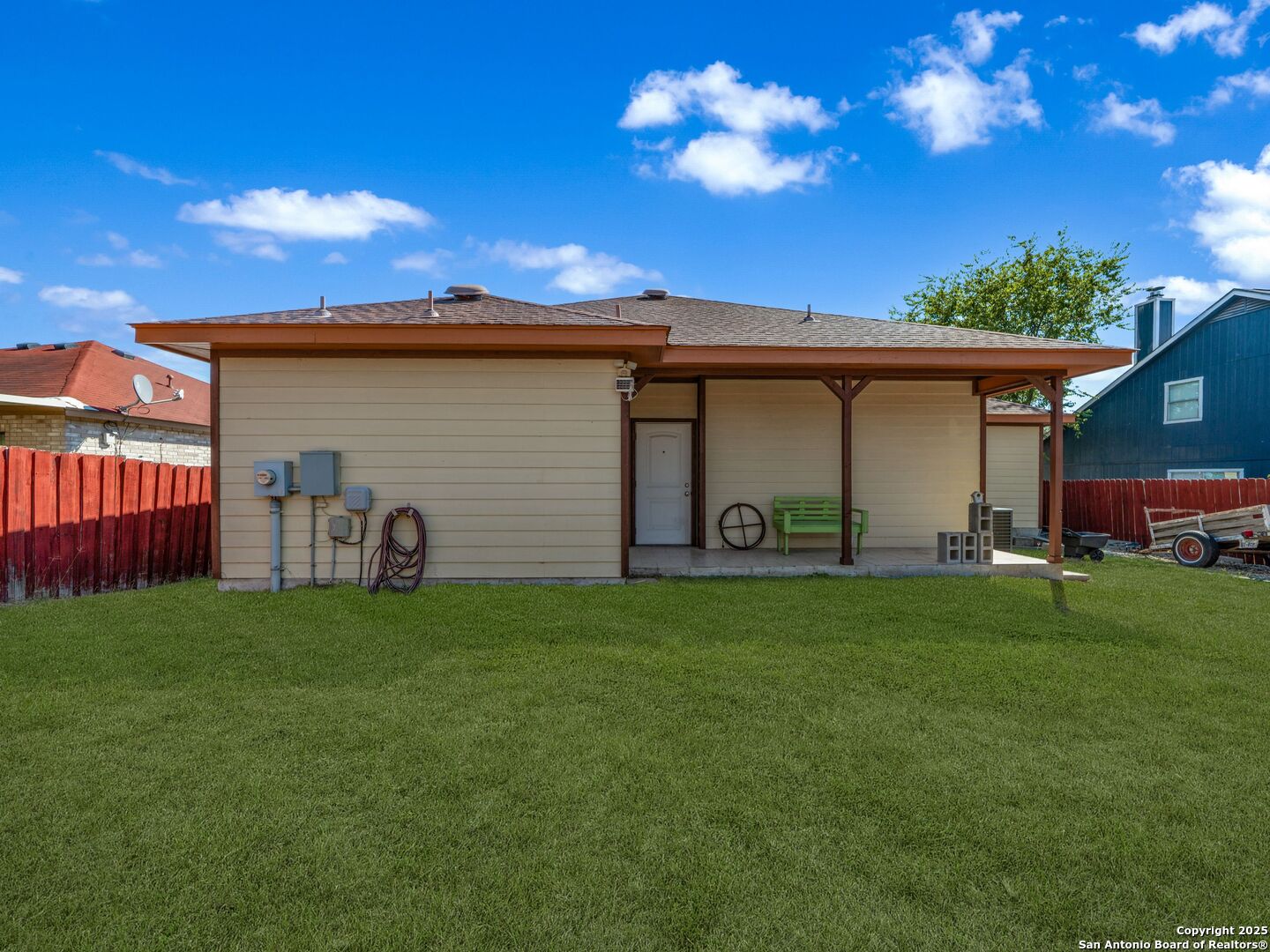 Rear of a single-story home with a covered patio and spacious green lawn.