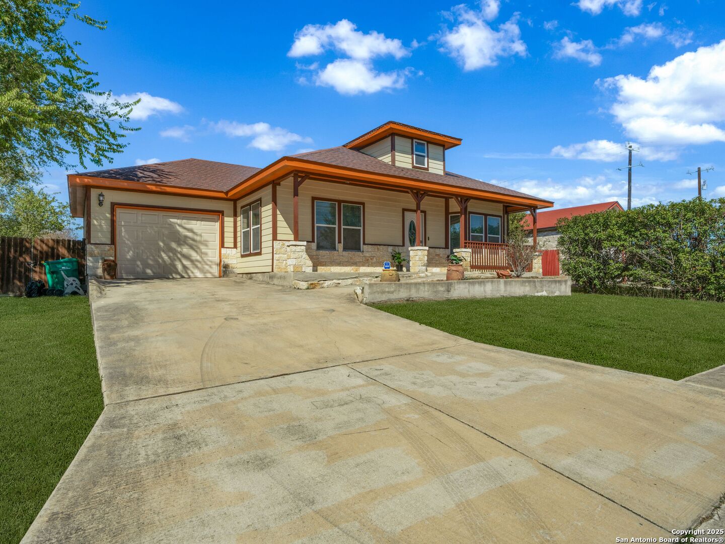 Single-story home with stone accents, a covered porch, attached garage, and broad concrete driveway.