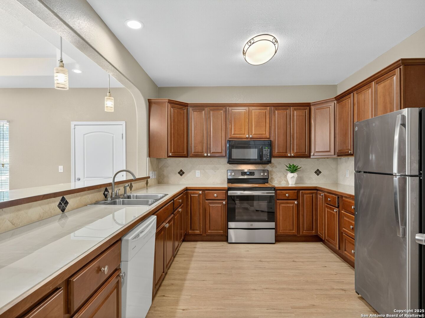Kitchen with wood cabinetry, light countertops, and stainless steel appliances.