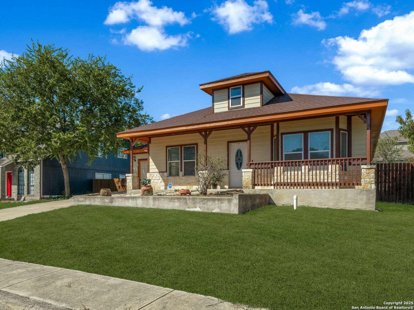 Home with a covered porch, stone accents, and a broad green front lawn.