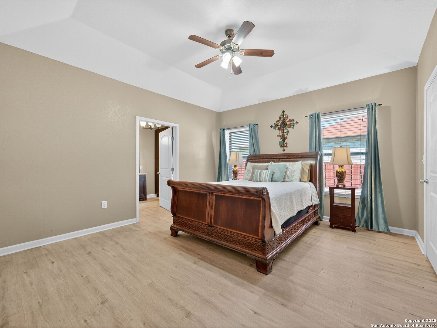Bedroom with an ornate dark wood bed, teal curtains, and light wood-look flooring.