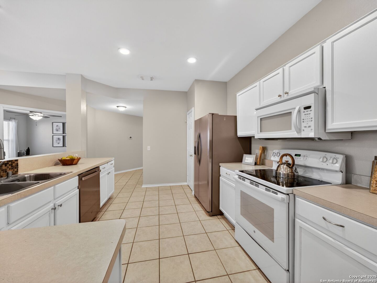 Kitchen with white cabinets, beige countertops, and stainless steel appliances.
