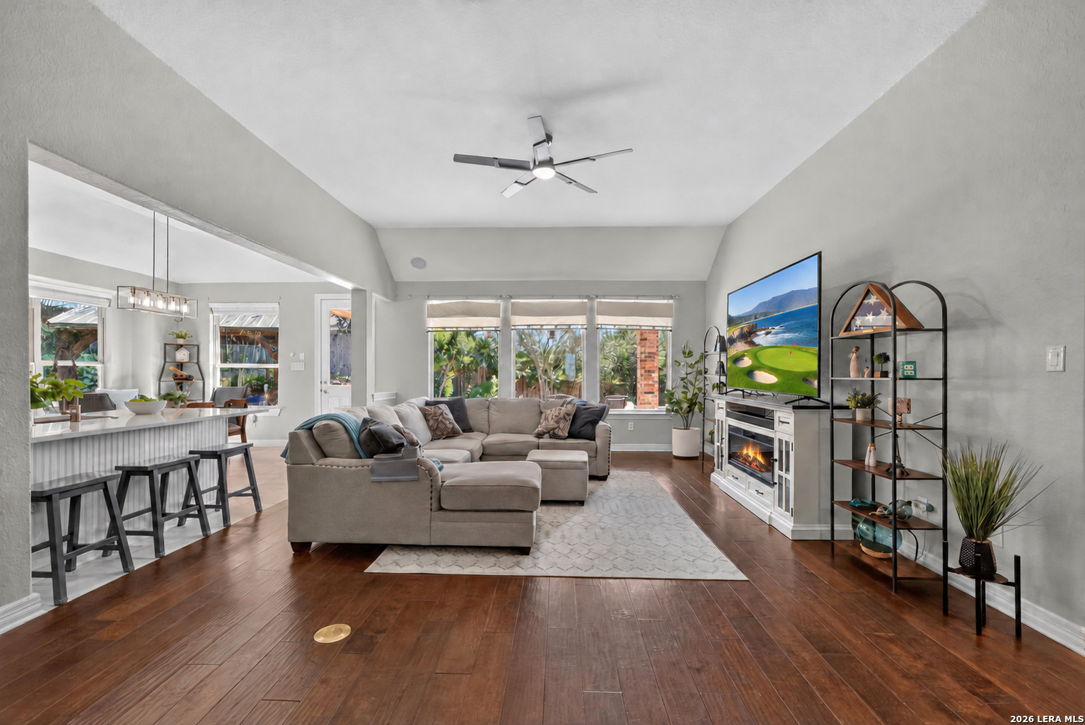 Living room with a sectional sofa, fireplace, and open connection to the kitchen and dining area.
