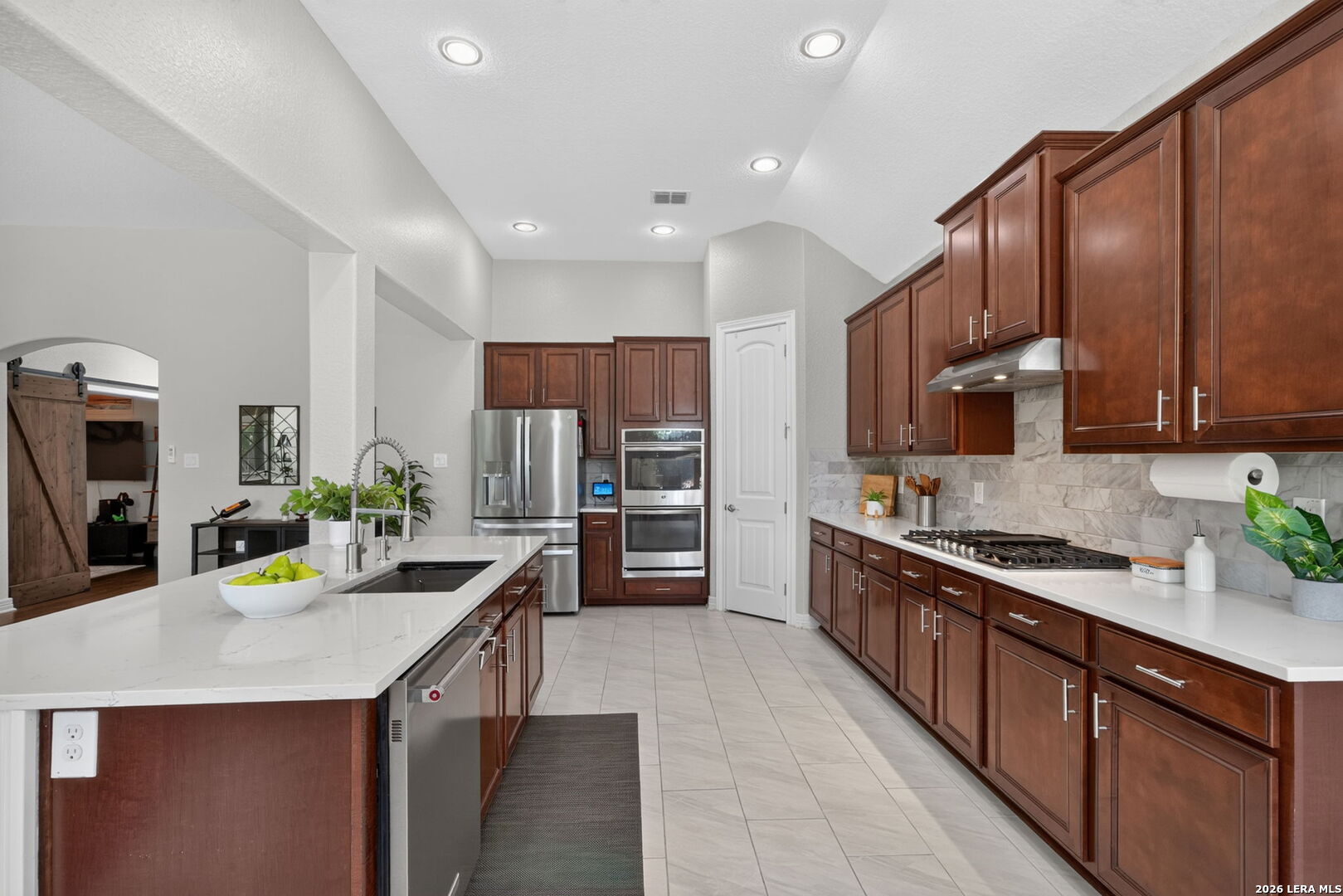 Kitchen with dark wood cabinets, white counters, stainless appliances, and a large island.