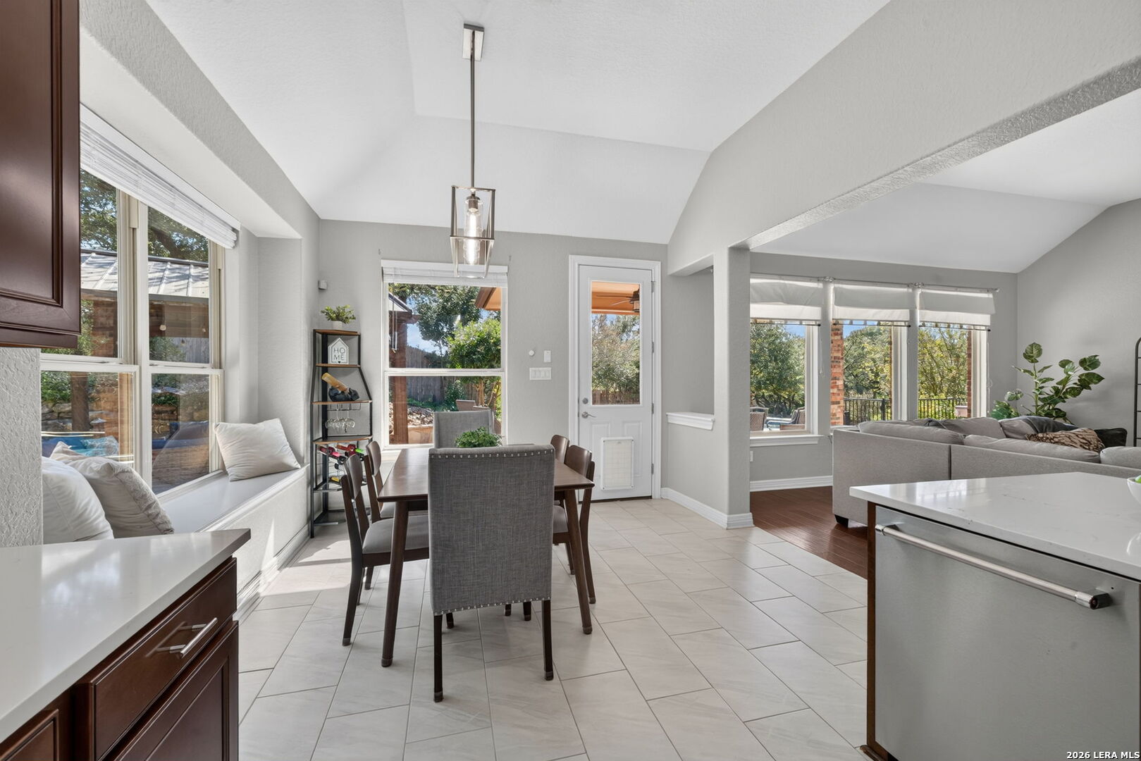 Dining area with tiled floors and a built-in window seat, open to a living room and kitchen.