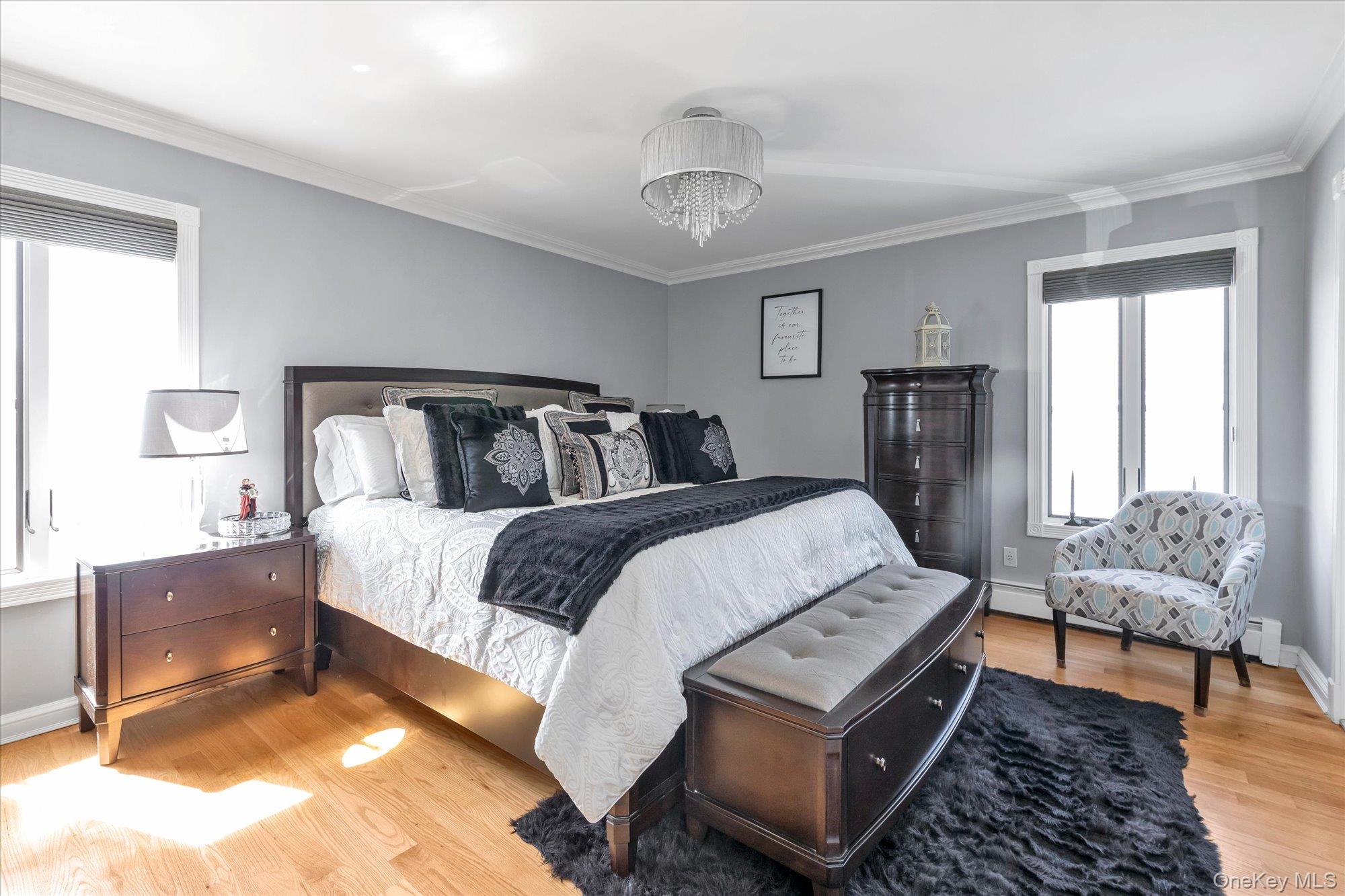 Furnished bedroom with a dark wood bed, charcoal accents, hardwood floors, and a patterned chair.