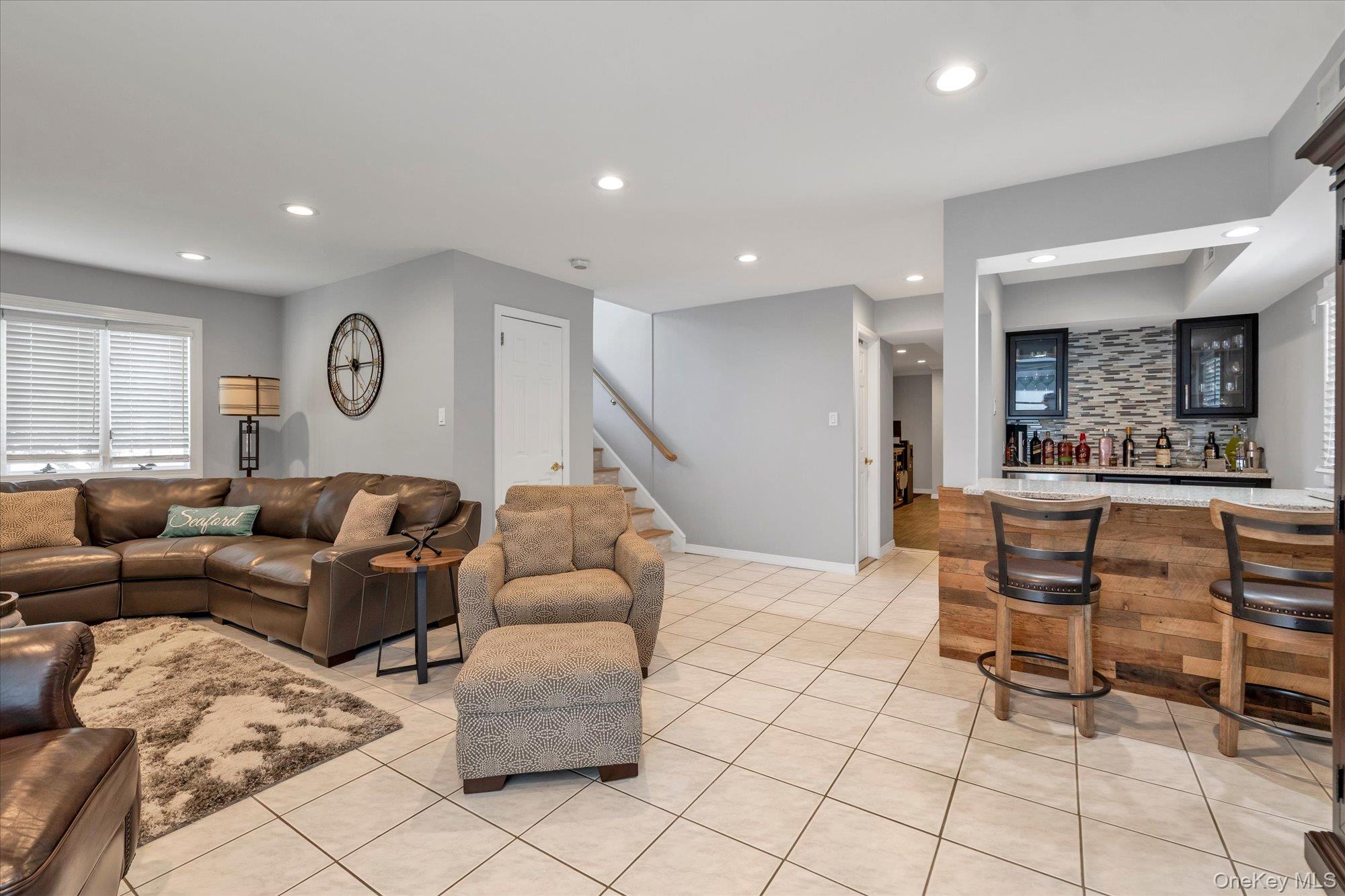 Furnished living room with a leather sectional and a built-in bar with wood-front cabinetry.