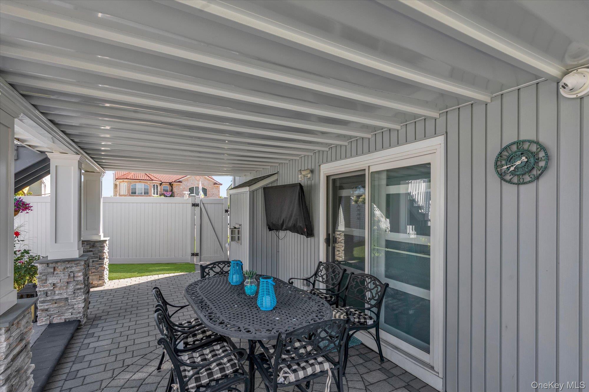 Covered patio with a metal dining set, paver flooring, and sliding glass doors.