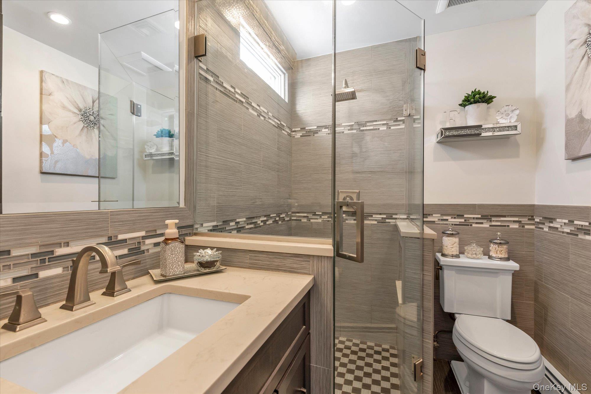 Bathroom with glass-enclosed tiled shower, checkerboard floor, and broad vanity countertop.