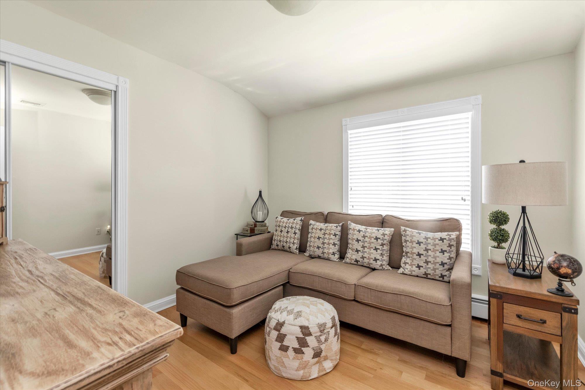 Furnished living room with a taupe sectional, patterned cushions, and hardwood floors.