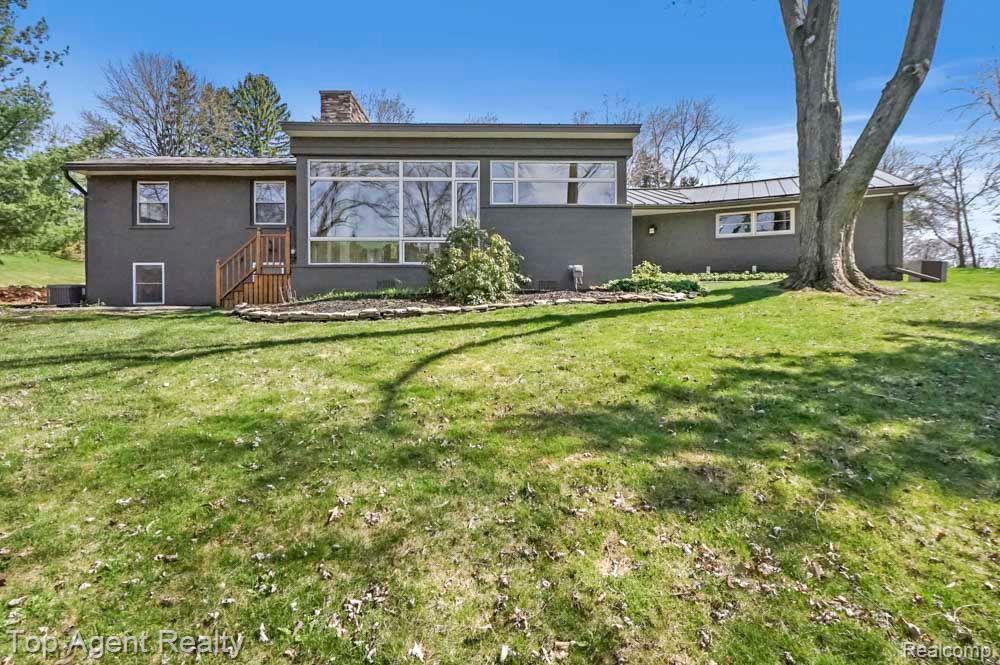 Dark-gray home with broad rear windows, a small deck, and a wide lawn.