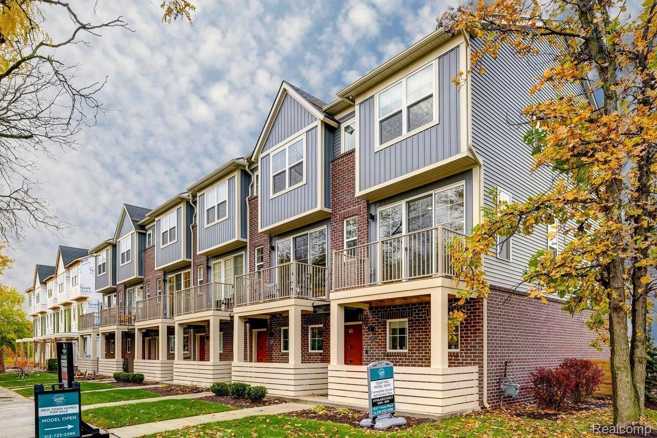 Row of brick and gray-sided townhomes with covered porches, balconies, and autumn trees.