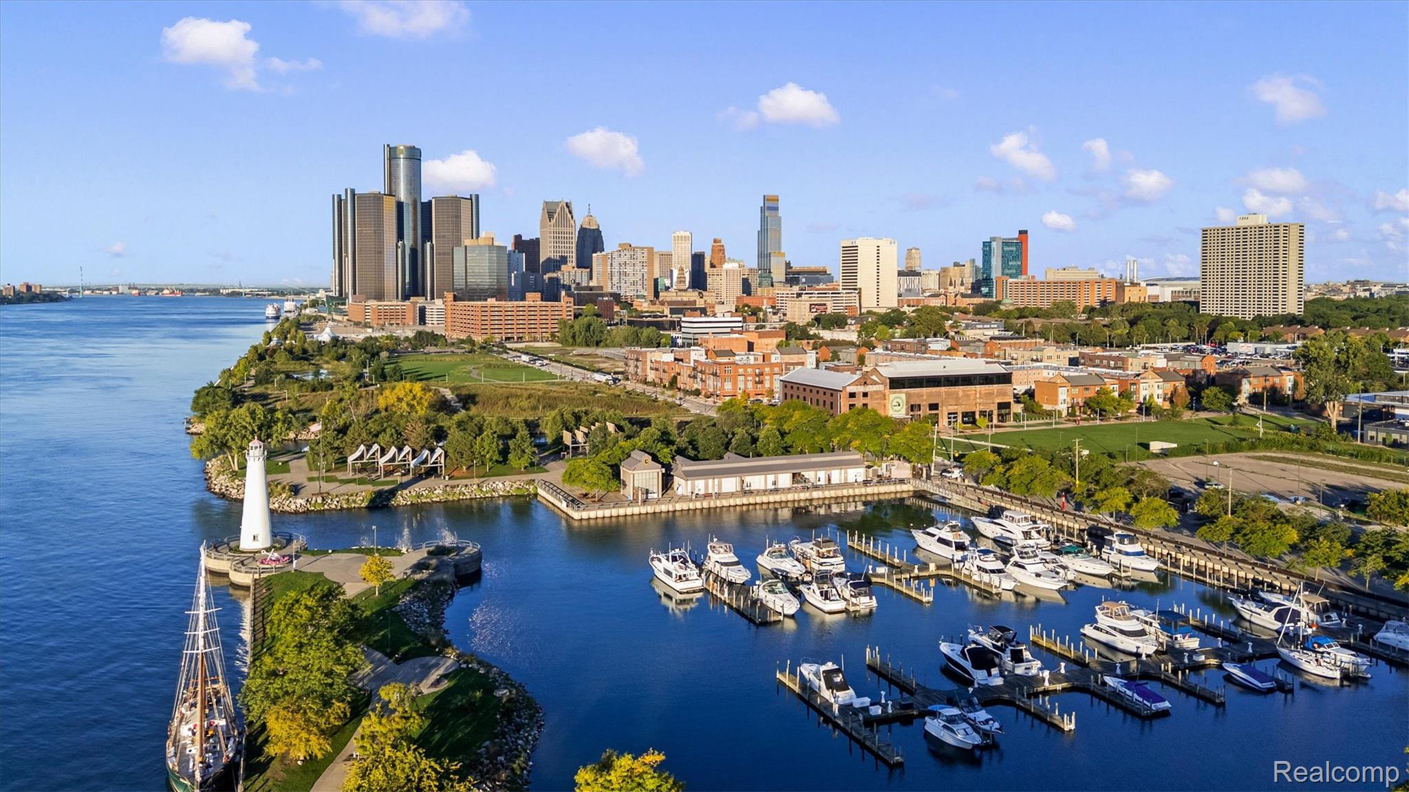 Detroit skyline across the river, with a marina and white lighthouse in the foreground.