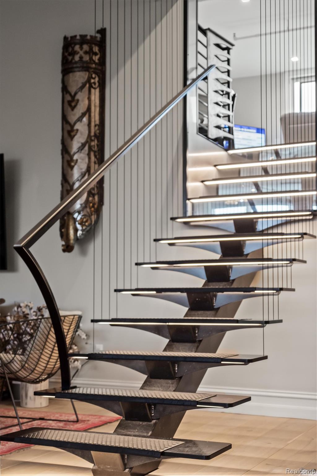 Floating staircase with dark open treads and slender vertical cable supports in a modern interior.