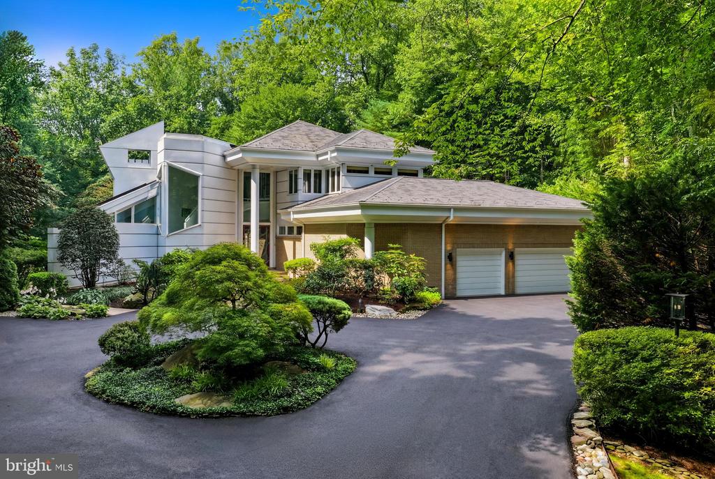 Modern two-story home with a curved driveway, landscaped island, and attached two-car garage.