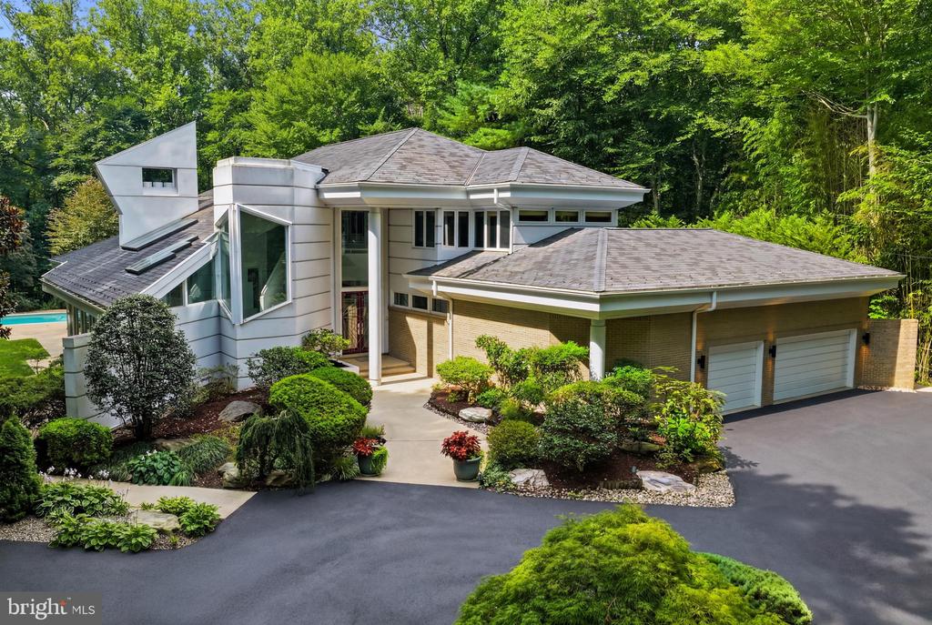 Contemporary Potomac home with angular white siding, brick two-car garage, and landscaped entrance.