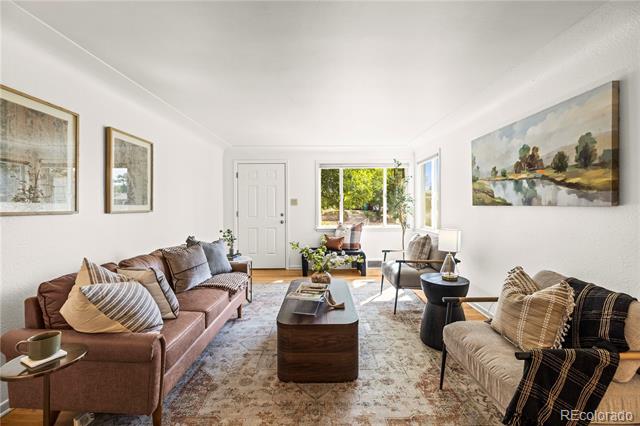 Furnished living room with two sofas, a patterned rug, and sliding glass doors opening to greenery.