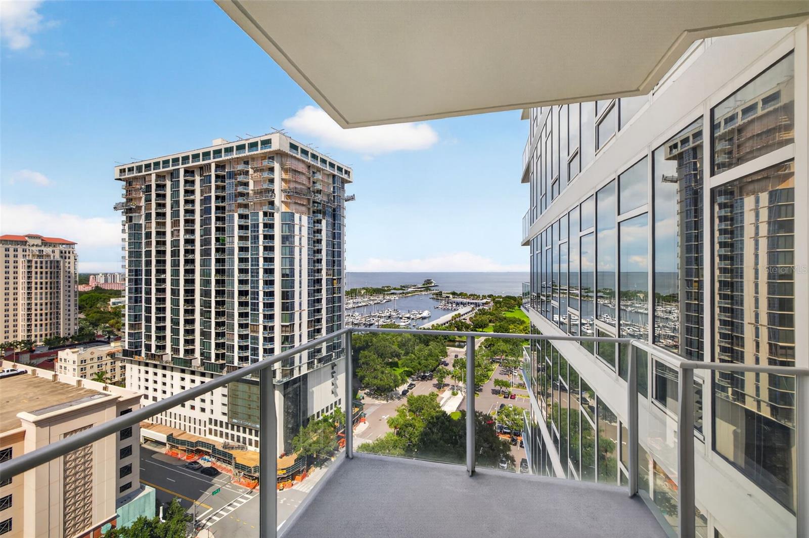 High-rise balcony overlooking downtown towers, a marina, and open water.