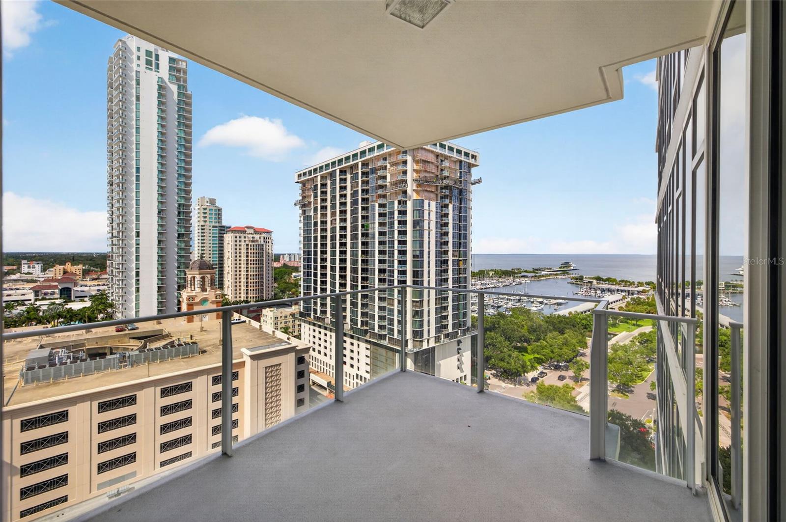 High-rise balcony overlooking downtown buildings, a marina, and open water.