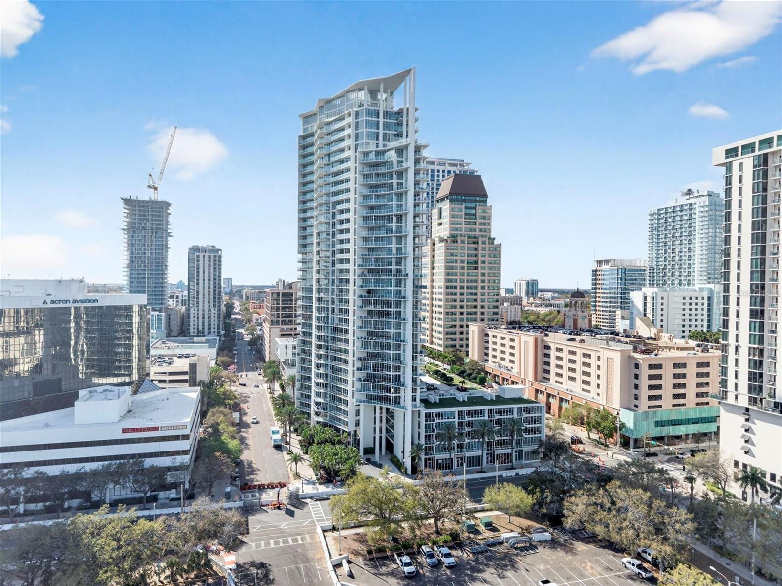 White-and-glass downtown condominium tower with an angled roofline and balconies, surrounded by city high-rises.