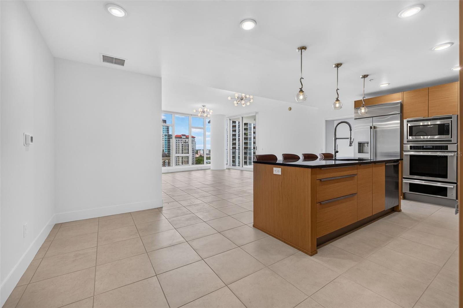 Condo kitchen with a wood-paneled island, stainless-steel appliances, and windows overlooking city buildings.