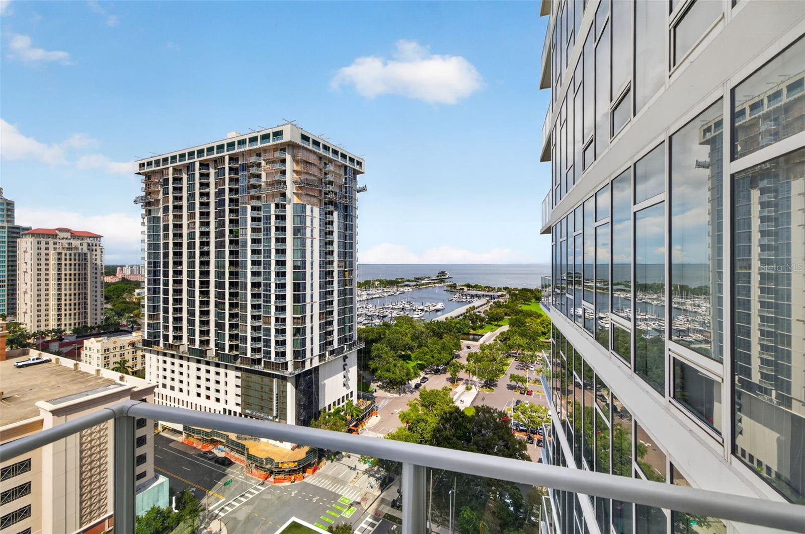 High-rise balcony view over downtown towers, a marina, and Tampa Bay.