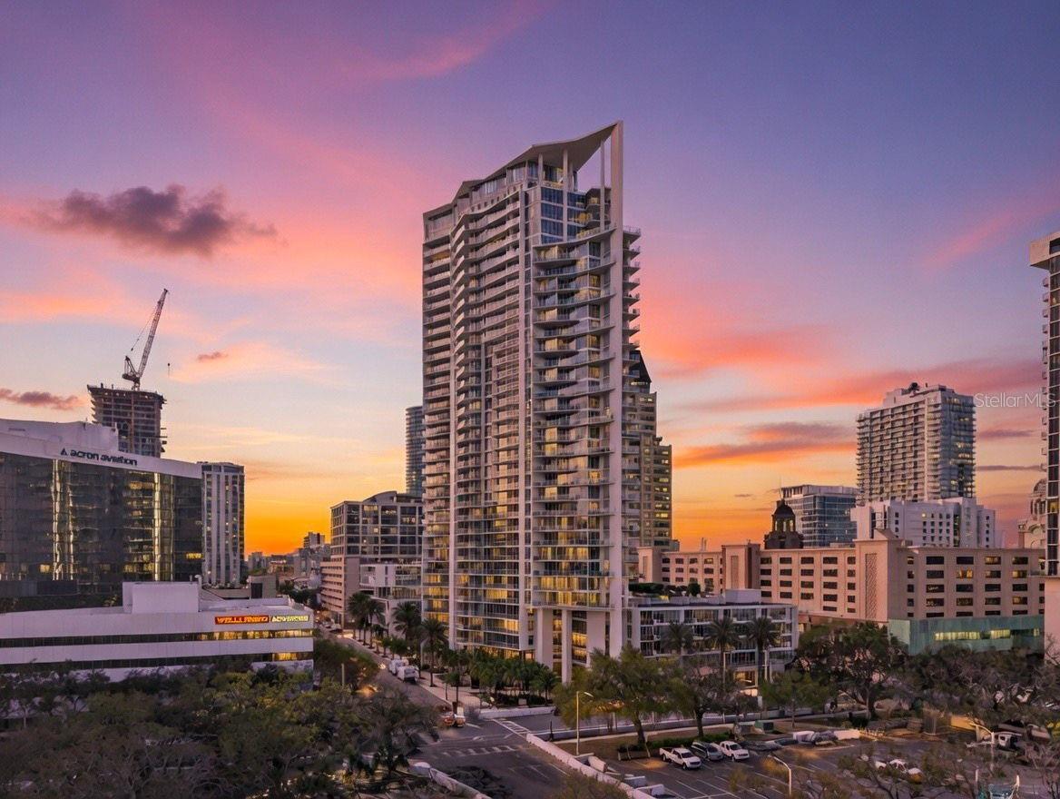 Downtown high-rise condominium with an angular roofline and glass balconies at sunset.
