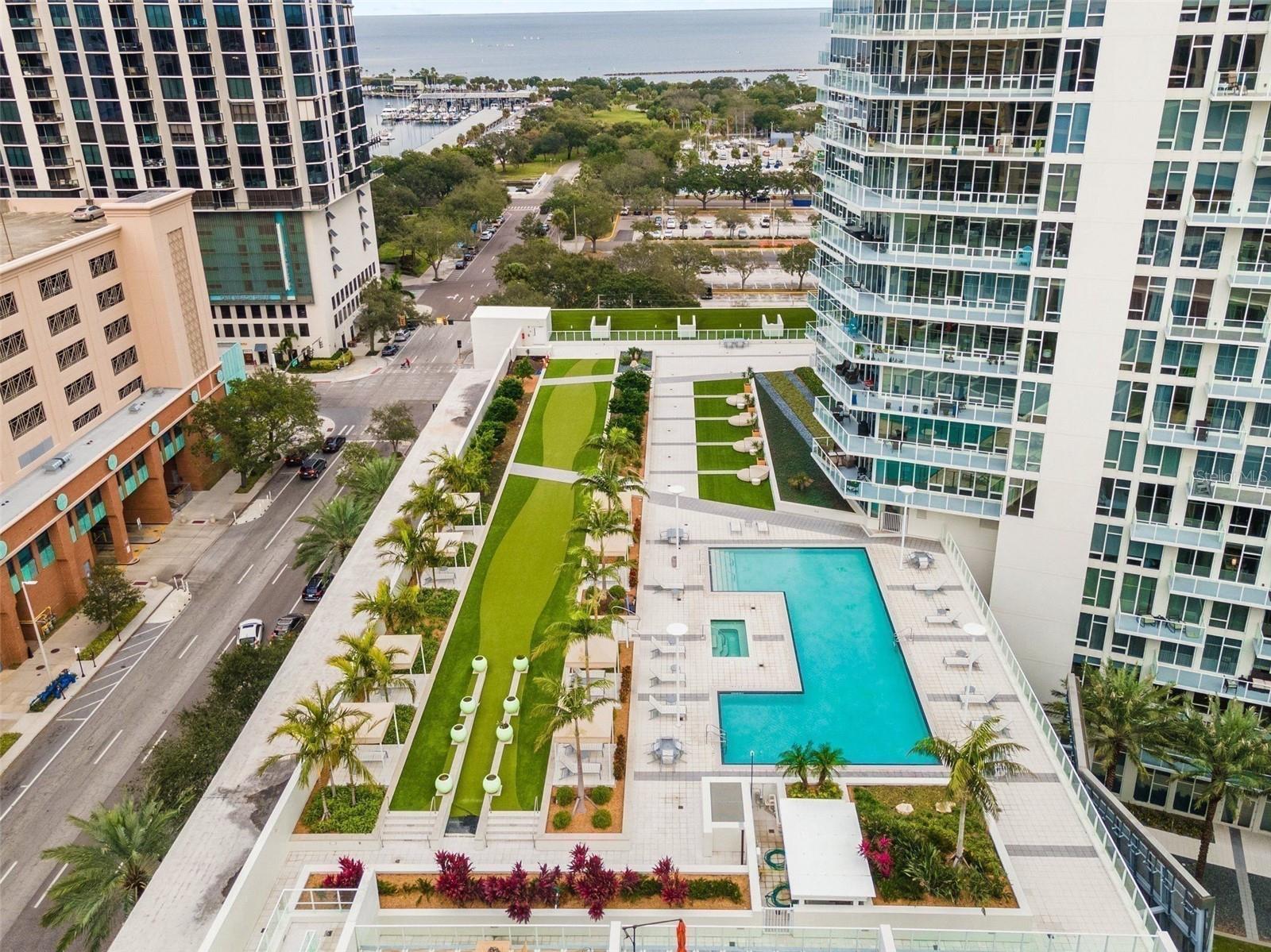 High-rise condominium courtyard with a pool and landscaped terrace overlooking the bay.