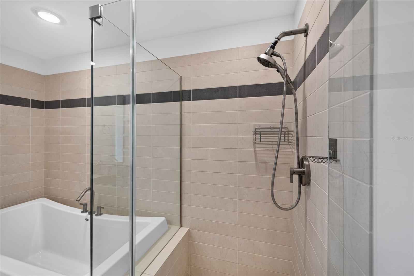Bathroom with a glass-enclosed tiled shower beside a built-in bathtub.