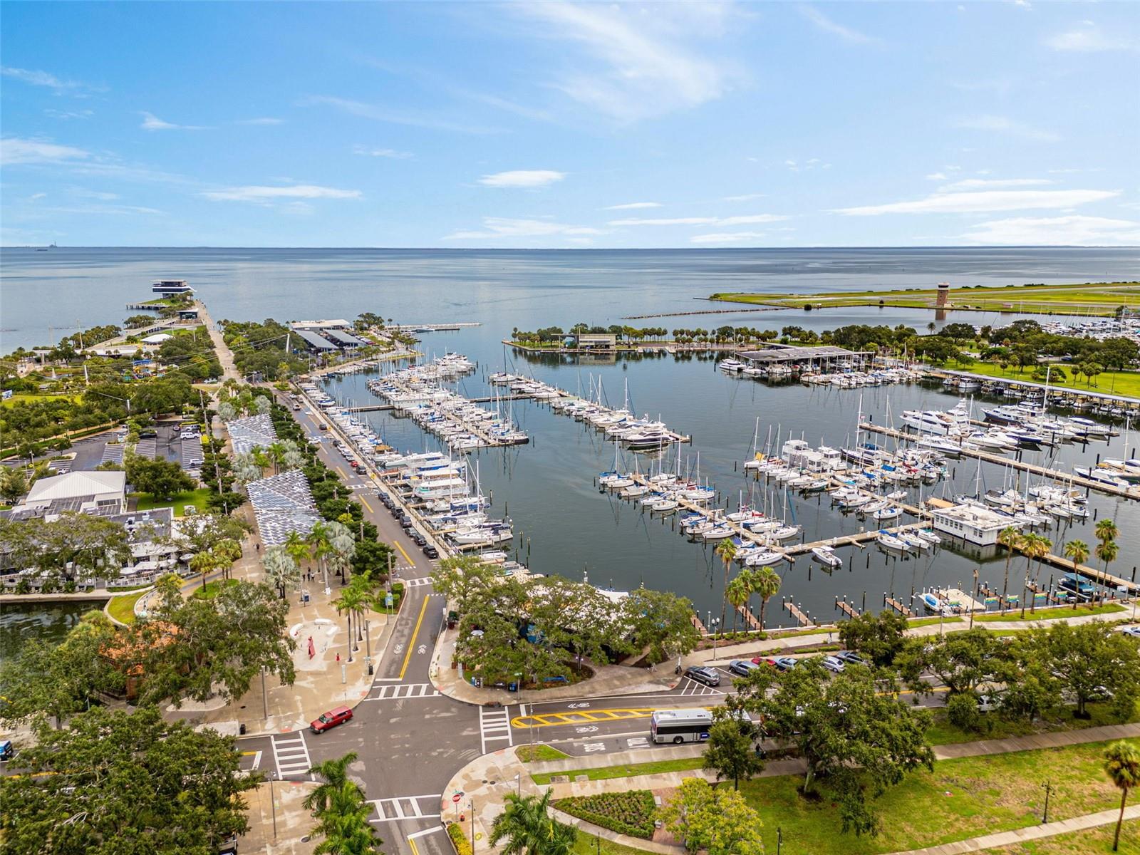 Aerial view of a marina packed with boats beside a broad bay and waterfront roads.