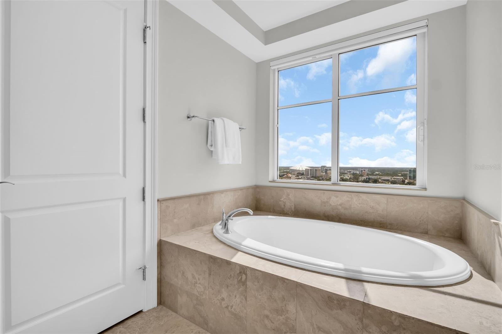 Bathroom with a built-in oval soaking tub and large window overlooking the city.