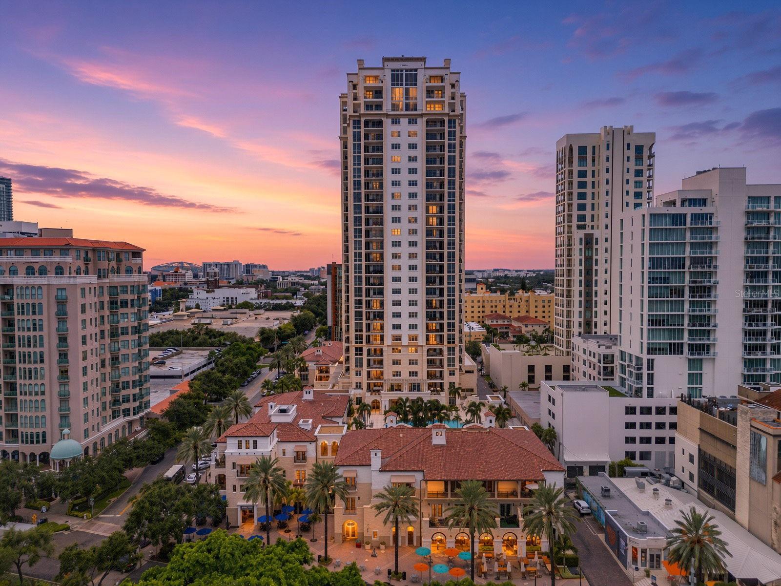 Downtown condominium towers at sunset, with a courtyard pool and city skyline.
