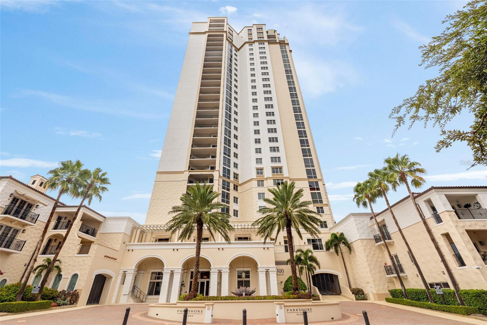 Parkshore Plaza condominium tower with palm trees framing its arched entrance.