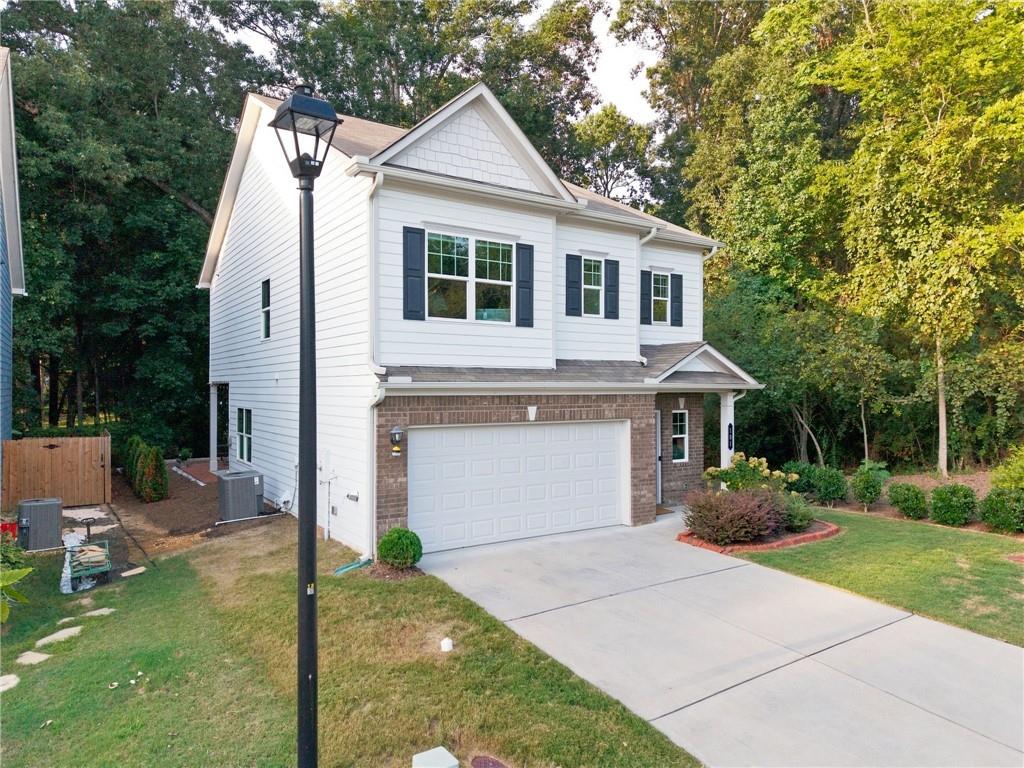 Two-story white house with brick facade, double garage, and wide driveway.