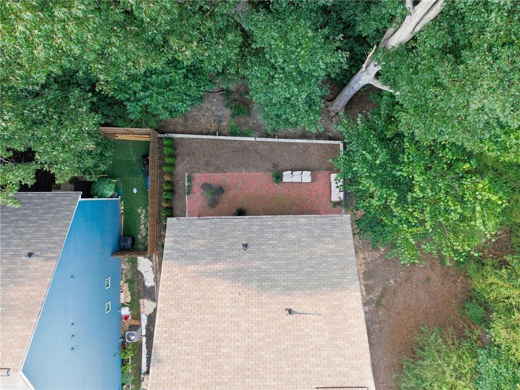 Aerial view of a home’s brick patio with outdoor seating, surrounded by mature trees.