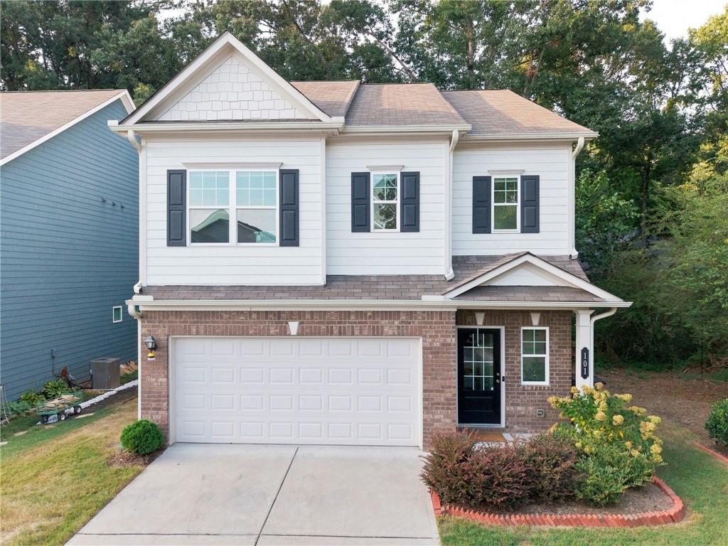 Two-story white-and-brick house with dark shutters, double garage, and landscaped front yard.