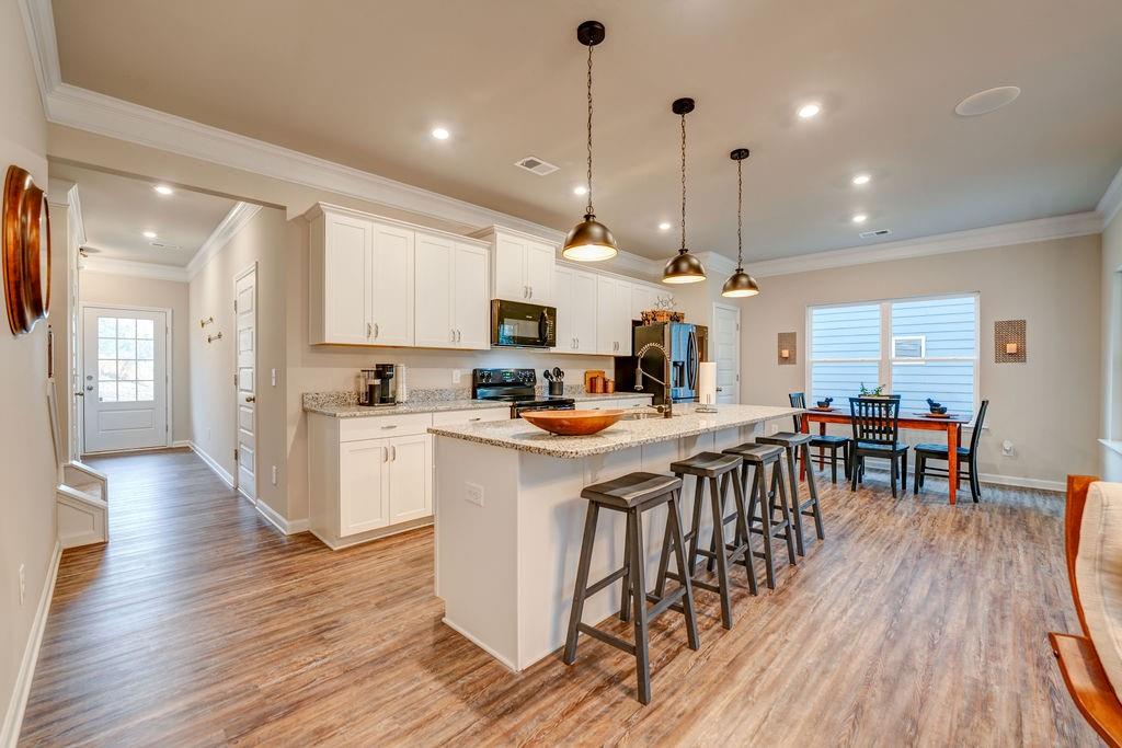 Open kitchen with a granite island and bar stools beside a dining area.