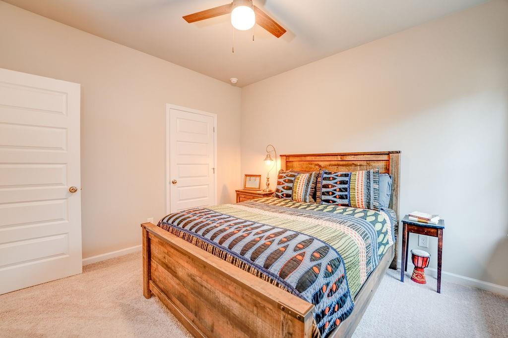 Bedroom with a wooden bed, colorful striped quilt, and ceiling fan.