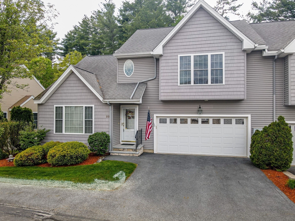 Gray two-story townhouse with an attached double garage and an American flag by the entrance.
