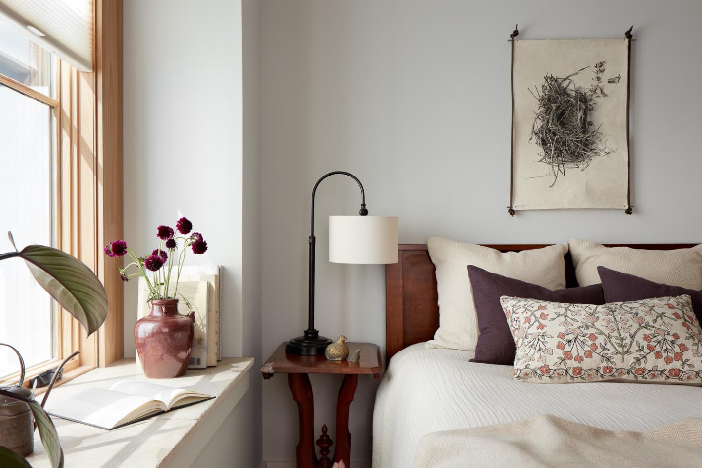 Bedroom with white bedding, a wood headboard, and a sunlit window with a reading nook.