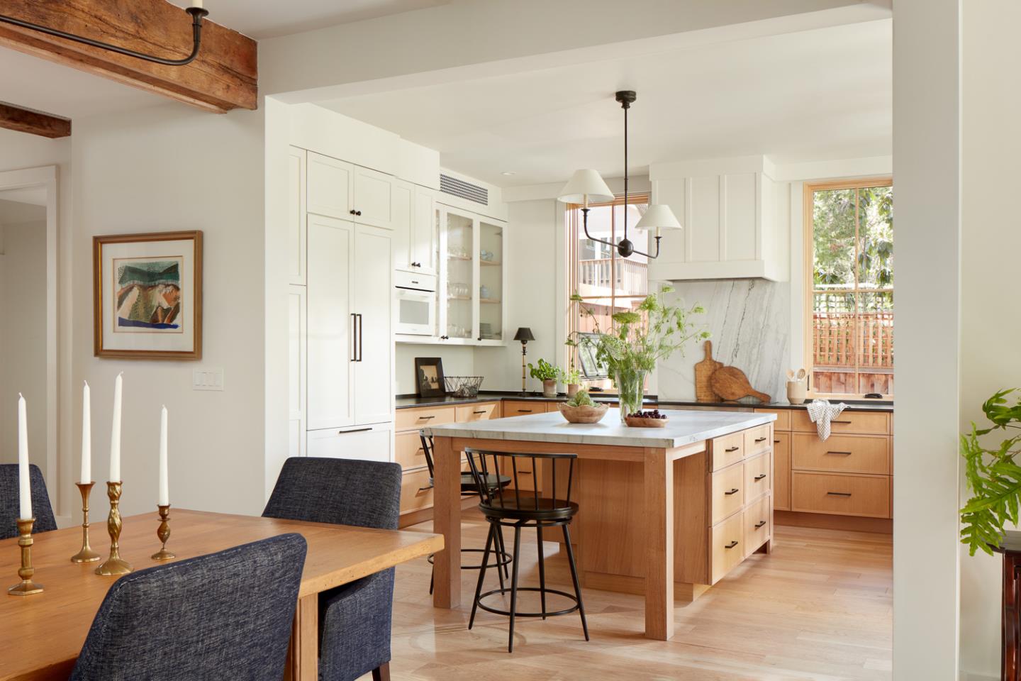 Bright kitchen with white cabinets, a large island, marble backsplash, and adjoining dining area.